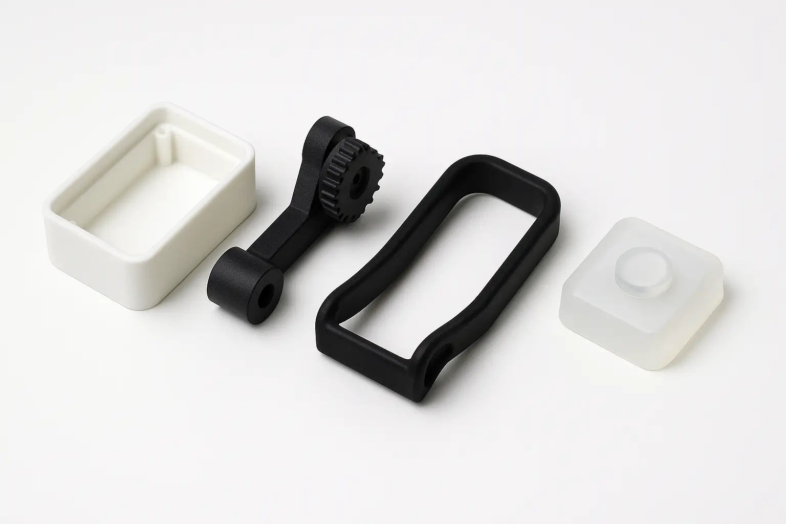Photo of four types of rapid prototyping materials: standard plastic, nylon, flexible TPU, and silicone, each shown as a finished 3D printed part
